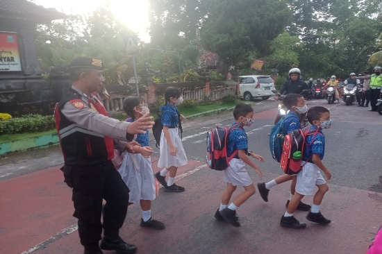 Panit Sabhara Polsek Gianyar Bantu Seberangkan Anak Sekolah