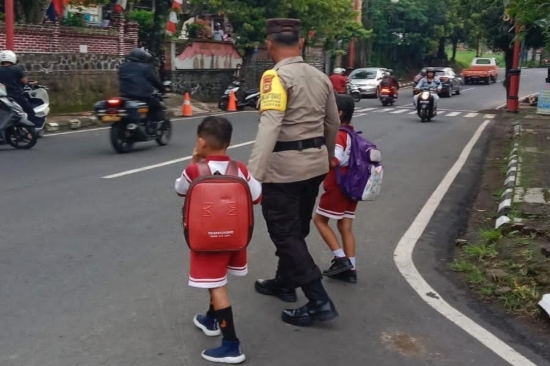 Potret Bhabinkamtibmas Kelurahan Gianyar Rutin Menolong Anak Sekolah Seberangi Jalan
