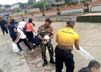 Babinsa bersama Pemerintah Desa Pemecutan Bersihkan Bantaran Tukad Badung dan Tabur Benih Ikan